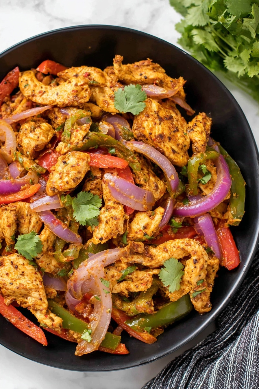 The dish is shown in a black bowl filled with several layers of cooked food. The base layer consists of light golden-brown cooked chicken pieces with a slightly seasoned texture. Mixed through the chicken are slices of red and green bell peppers, and purple-red onion strips, all appearing soft with a slight char. Scattered on top are a few fresh green cilantro leaves adding a fresh contrast. The bowl is placed on a white marbled surface, with a small bunch of green cilantro visible on the top right and a striped cloth partially seen on the bottom right side. photo taken with an iphone --ar 2:3 --v 7