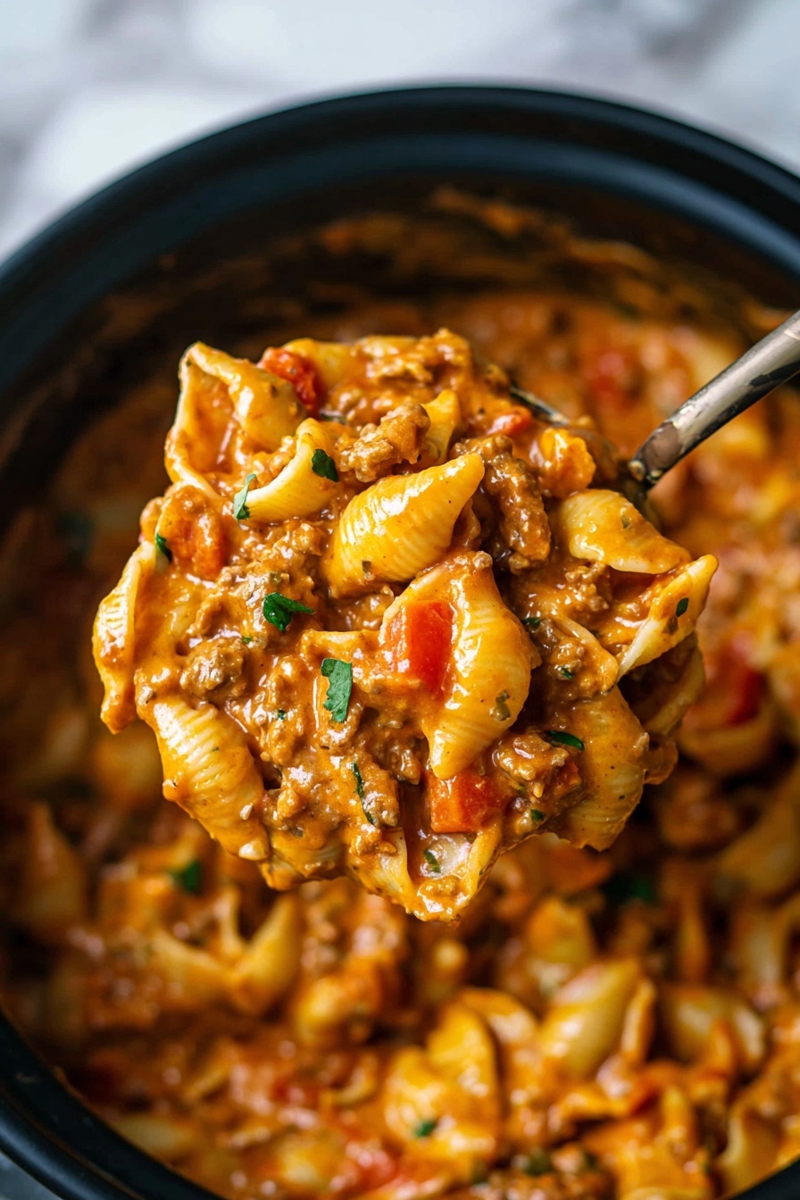 The image shows a close-up of a spoon full of pasta shells mixed with a thick, creamy, orange-colored sauce from a pot. The pasta is layered with small chunks of red bell peppers, bits of ground meat, and some green herb pieces sprinkled on top. The sauce covers the pasta evenly, giving it a glossy texture. The pot holding the pasta is black, and the background has a white marbled surface. photo taken with an iphone --ar 2:3 --v 7