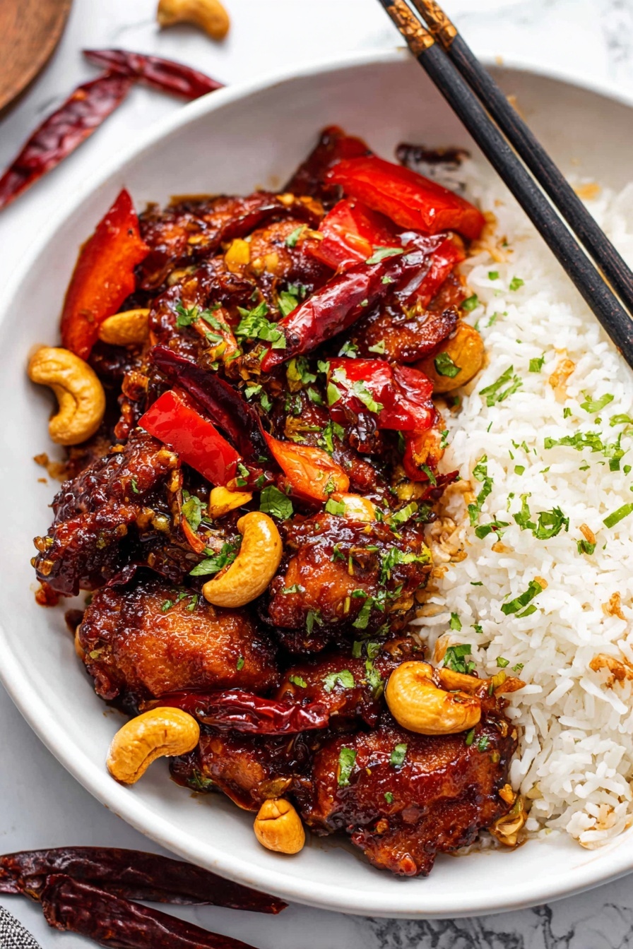 A silver pan is filled with three layers of ingredients. The bottom layer is light brown cashew nuts, spread evenly across the pan base. On top of them lies thin, curved slices of purple-red onion, mostly gathered on one side of the pan. The top layer is made of bright red bell pepper strips, piled loosely in the center, along with a few dark red dried chili peppers scattered among the bell pepper. The pan is set on a stovetop with a white marbled surface around it. Photo taken with an iphone --ar 2:3 --v 7