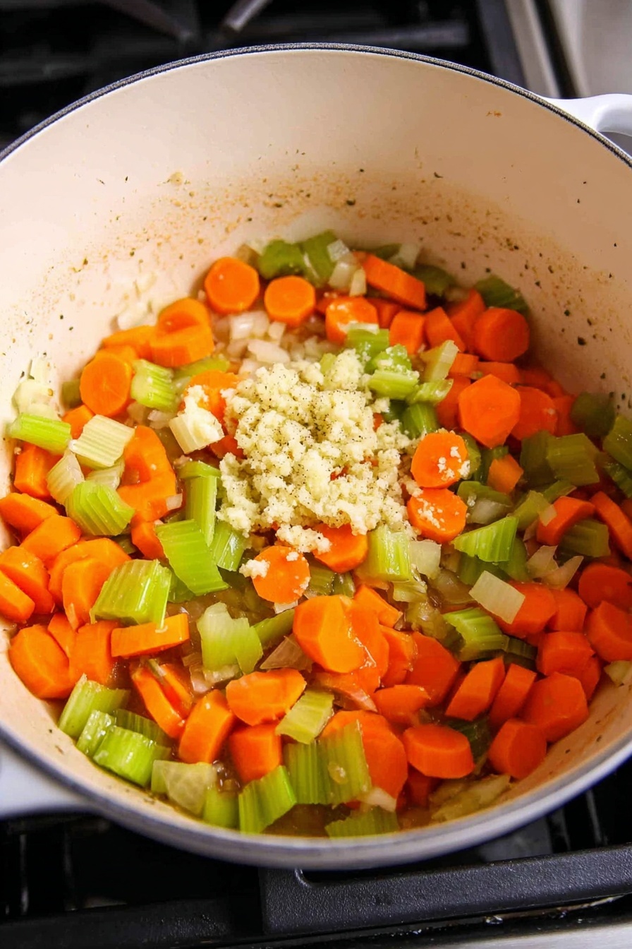 The image shows a creamy soup in a white bowl with a light brown rim, placed on a white marbled surface. The soup has thick white noodles mixed with small pieces of light beige chicken, orange carrot slices, and green celery pieces. The top is sprinkled with bright orange shredded cheese and chopped green onions, with visible black pepper specks. A gold spoon is resting inside the bowl, partially submerged in the soup near the lower right side. In the background, there is a small wooden bowl with green onion slices and some scattered green onion pieces. Part of a striped cloth napkin with white and yellow stripes is just visible below the bowl on the marble surface. photo taken with an iphone --ar 2:3 --v 7